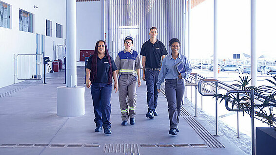 Four Leadec employees walking along a corridor inside a building.