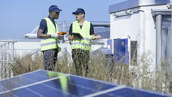 Two Leadec employees on factory roof with photovoltaic panels.